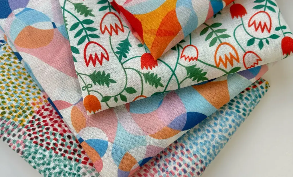 a stack of custom printed lightweight linen fabric featuring bright vibrant summer designs